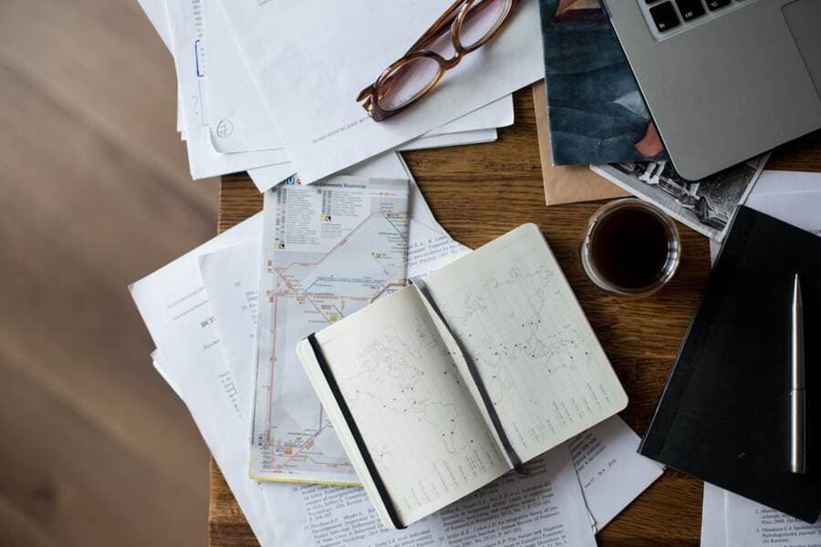 Papéis, caderno e café sobre a mesa para planejar a mudança Papéis, caderno e café sobre a mesa para planejar a mudança