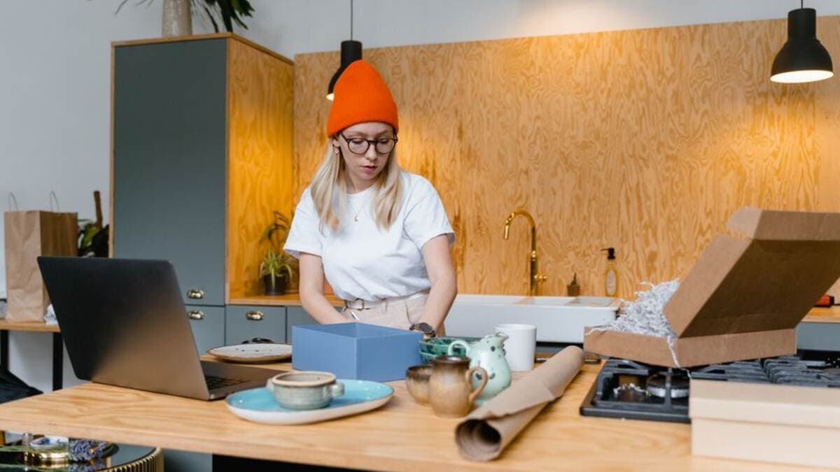 Mulher organizando caixas de mudança ao lado do notebook