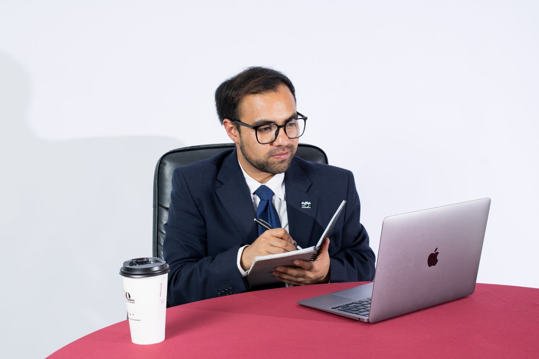 Onboarding remoto: como funciona na prática Professional businessman taking notes at a desk with a laptop and coffee. Ideal for office themes.