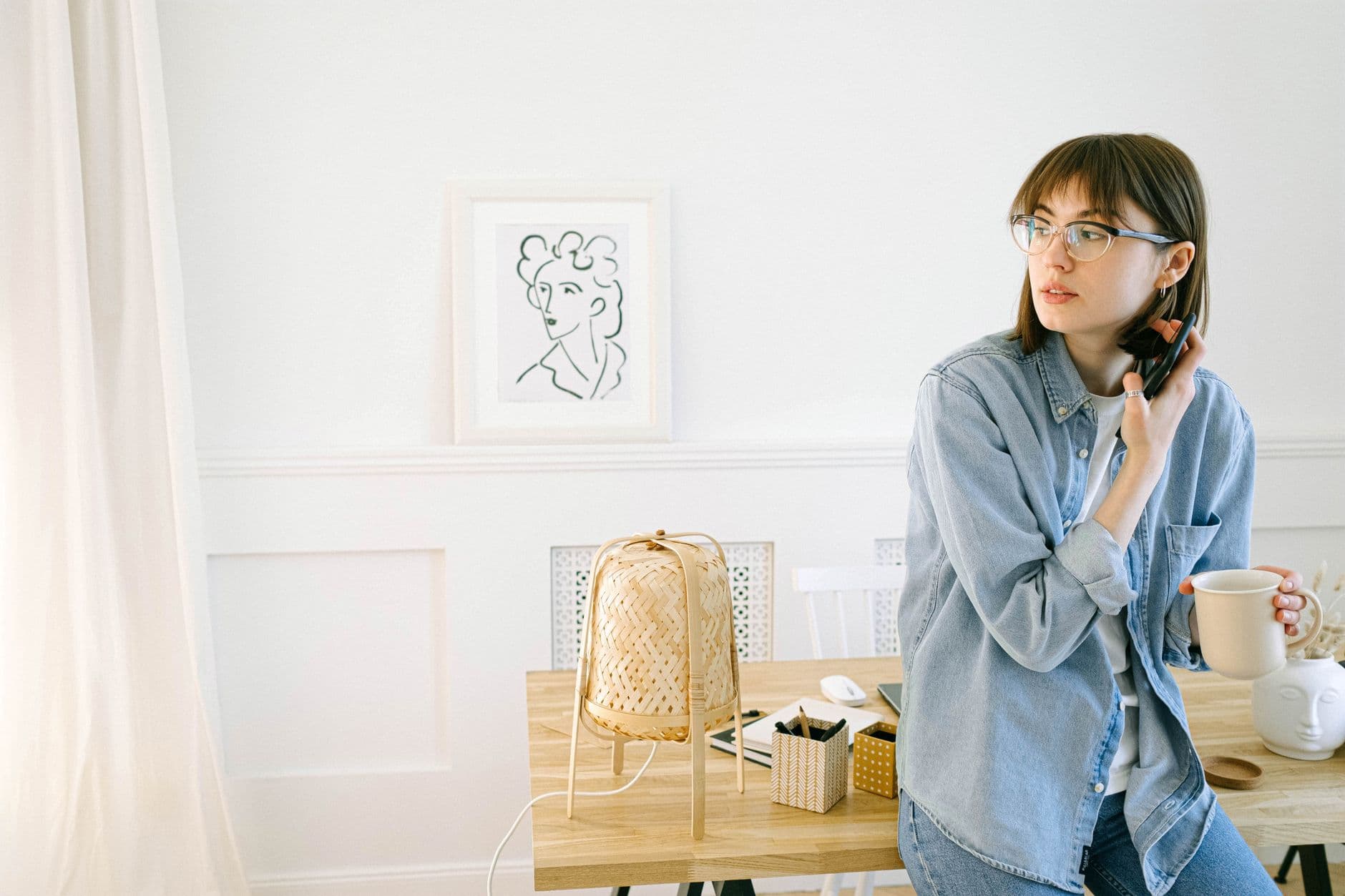 Pausas ativas cronometradas no home office Young woman in a casual home office setting holding a mug, symbolizing a modern work-from-home lifestyle.