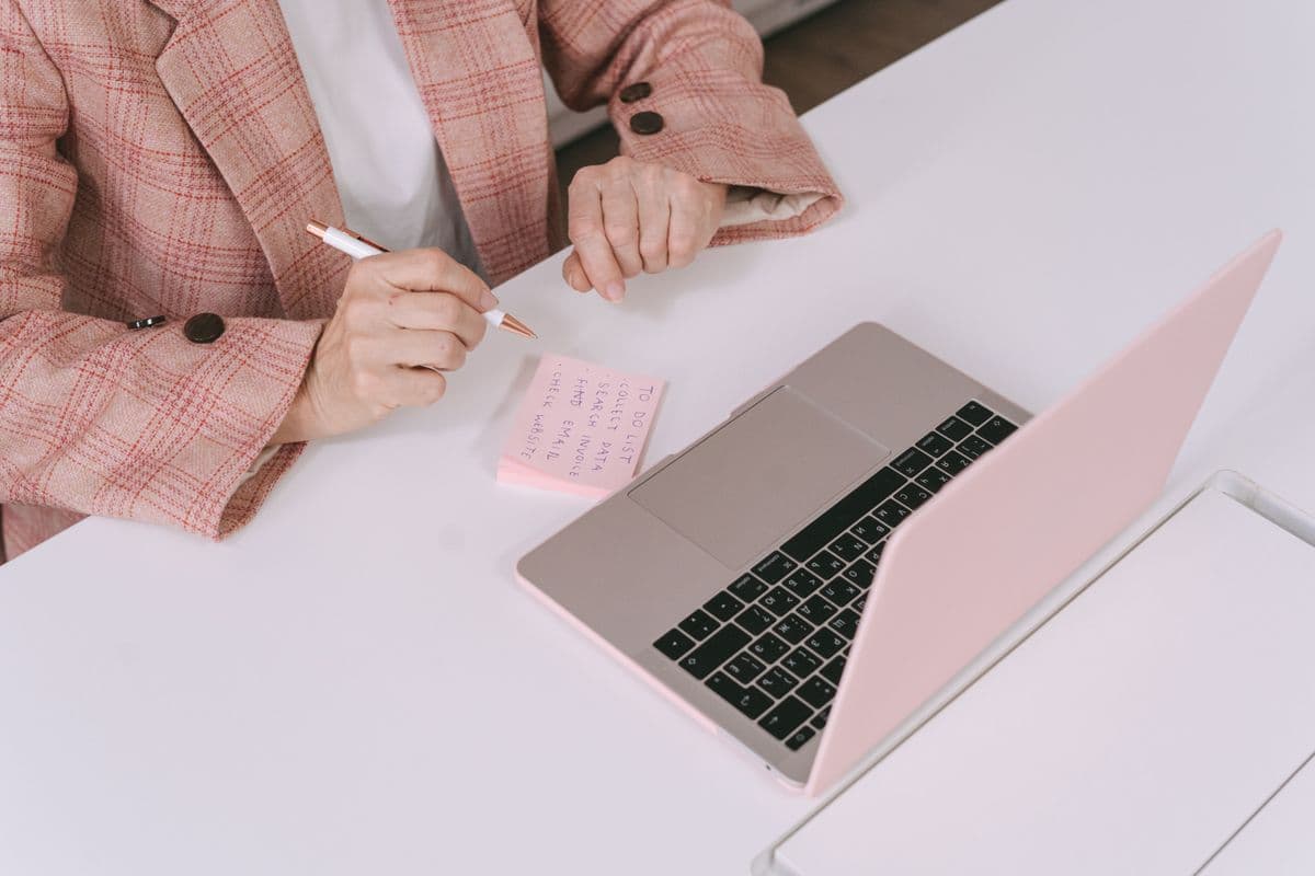 Pessoa organizando tarefas em um planner ao lado de um notebook no home office
