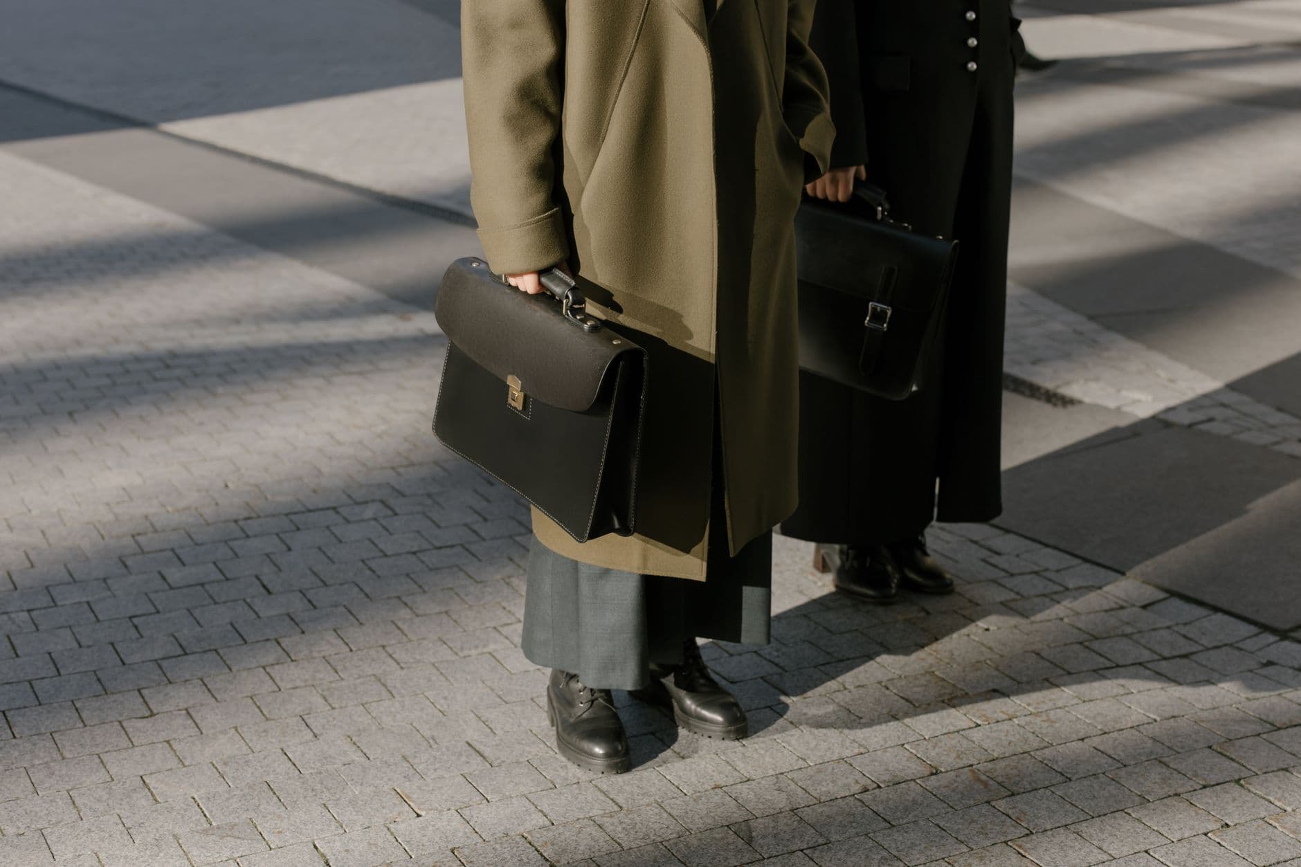 Ritual de encerramento do expediente remoto Two business professionals in coats walking with briefcases in an urban setting.