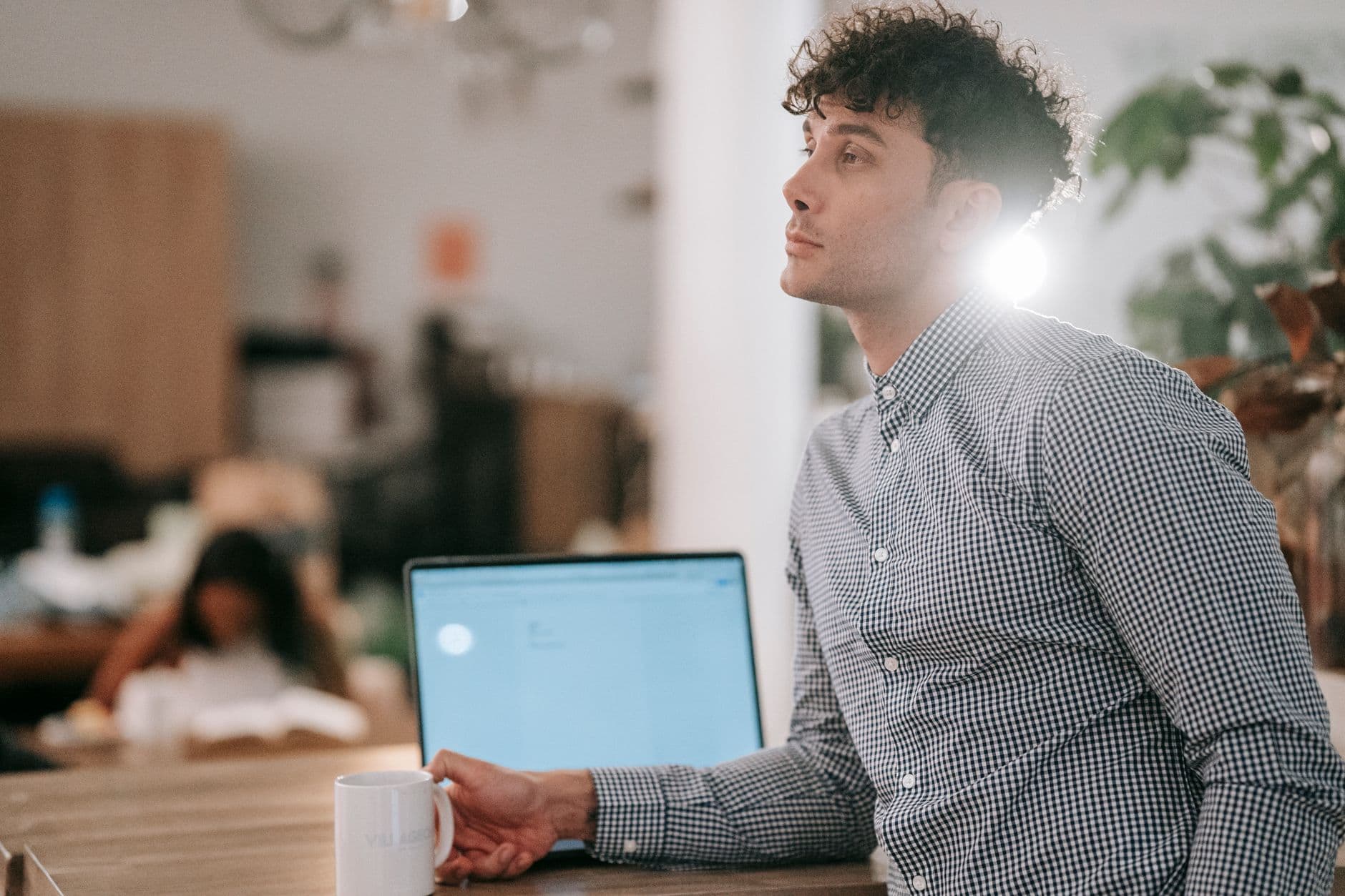 Como montar uma rotina para home office Young man in a café working on a laptop, enjoying a coffee break. Relaxed atmosphere and stylish attire.