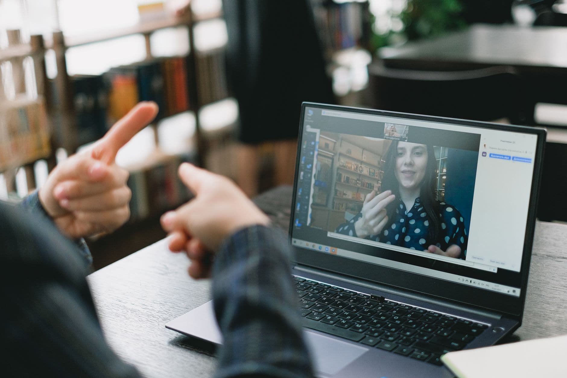Slack vs Teams: qual escolher no trabalho remoto Crop anonymous woman teaching sign language to female student during video call via laptop in light workspace