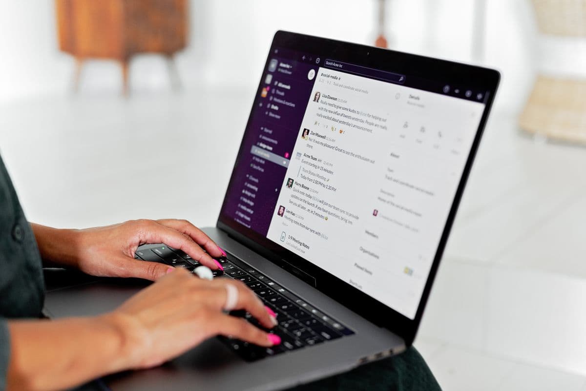 Pessoa trabalhando em casa diante de um notebook com notificações de mensagens na tela