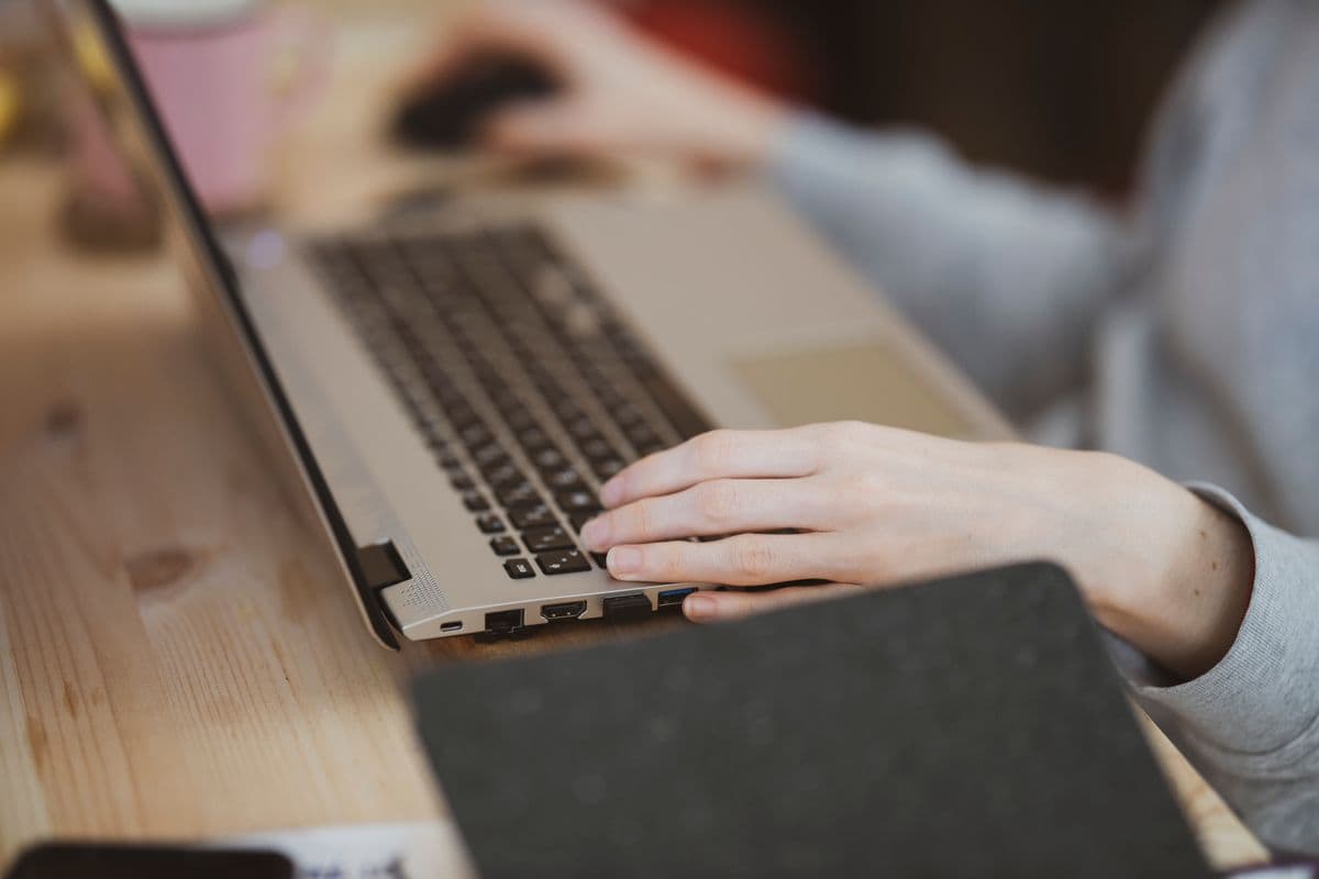 Pessoa trabalhando com notebook elevado em uma mesa organizada de home office