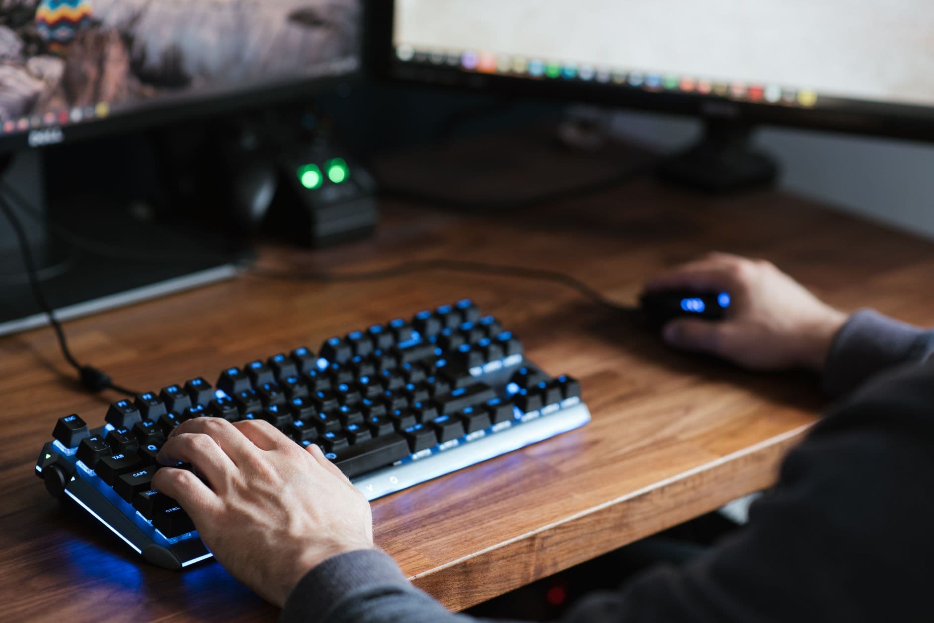 Pessoa trabalhando em casa com teclado e mouse ergonômicos sobre uma mesa organizada.