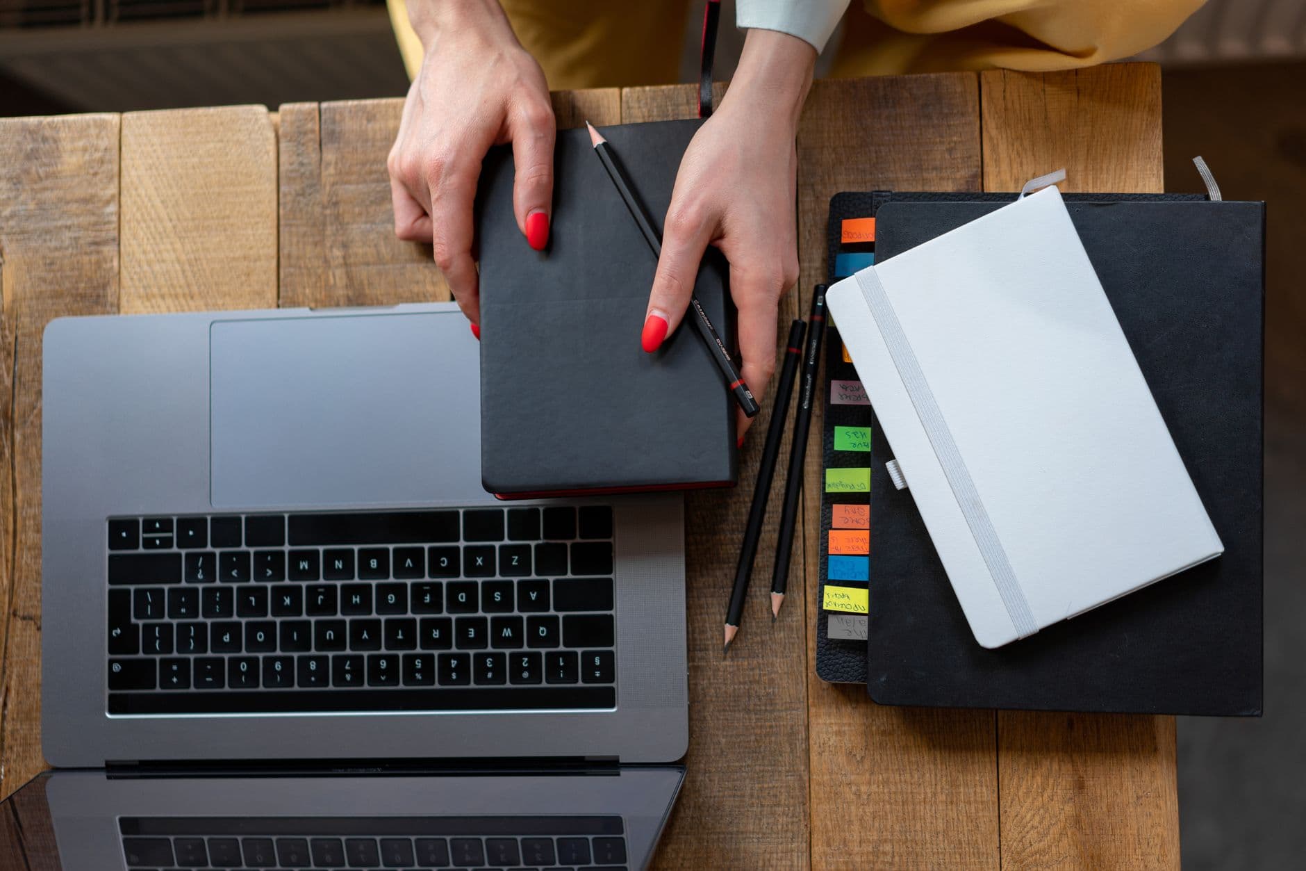 Pessoa trabalhando no laptop em uma mesa organizada de home office com agenda aberta