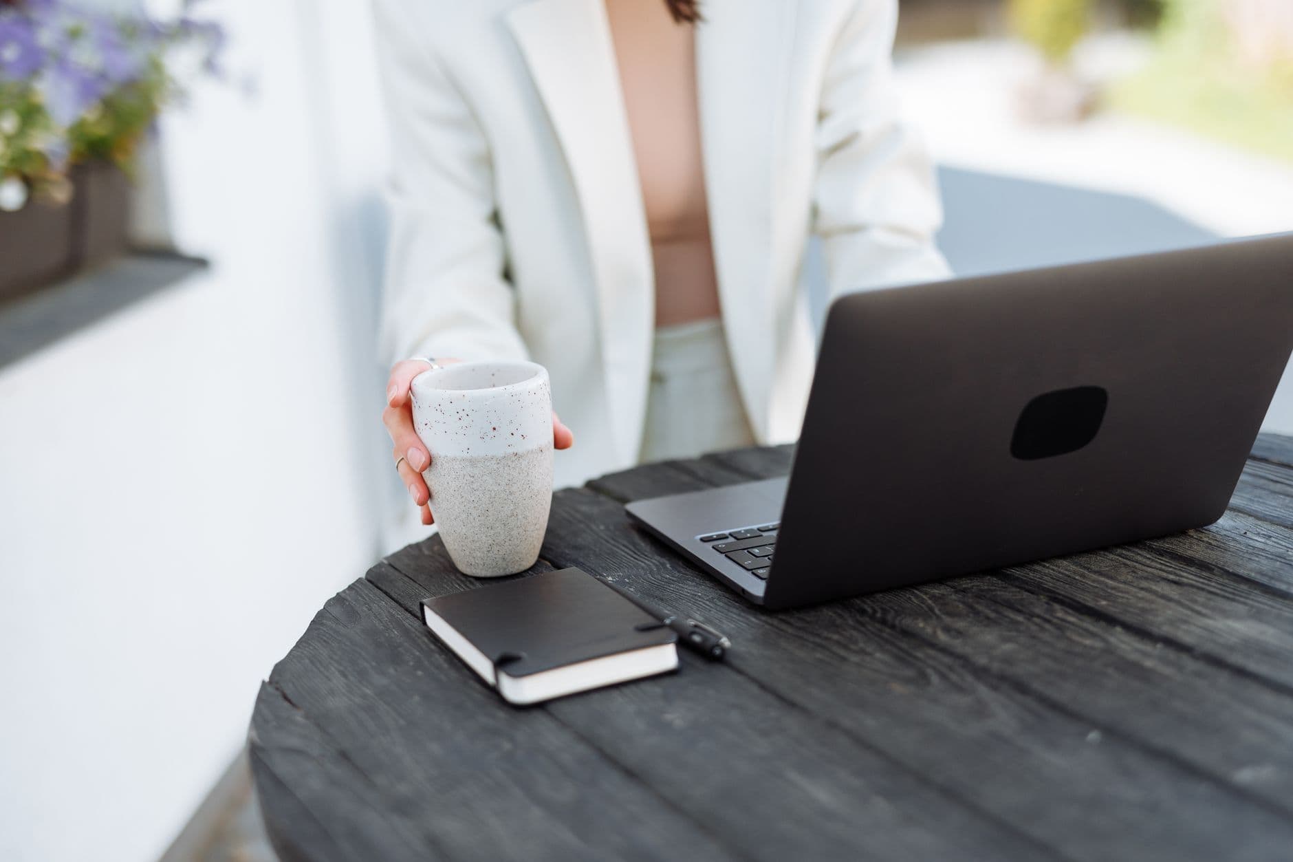 Técnica time blocking no home office: como aplicar Businesswoman using laptop outdoors with coffee mug, in a casual setting.