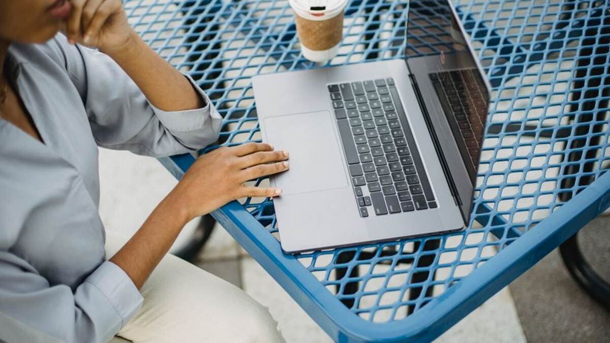 Pessoa trabalhando no notebook em uma mesa de cafeteria
