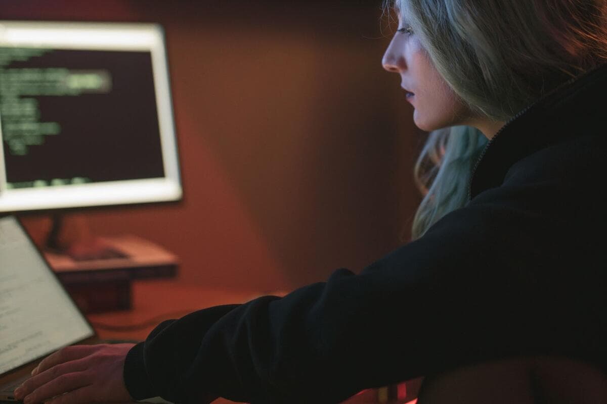 Mulher trabalhando à noite no notebook com código na tela