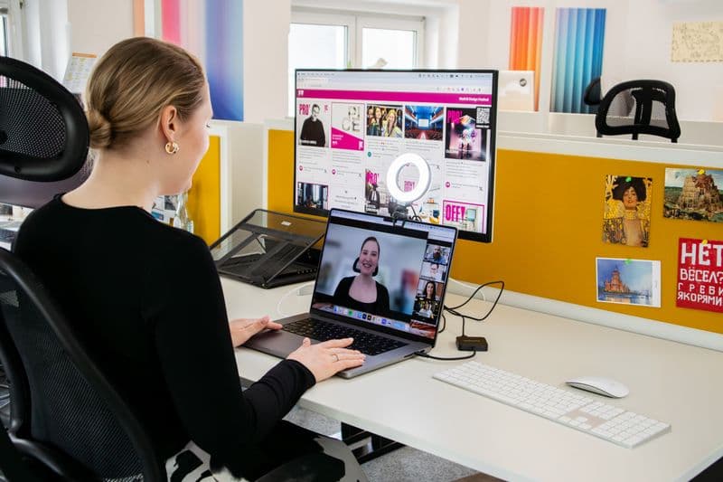 Trabalho remoto aumenta ou reduz a jornada real de trabalho Woman engaged in a video call at her office desk, using technology for remote work and communication.
