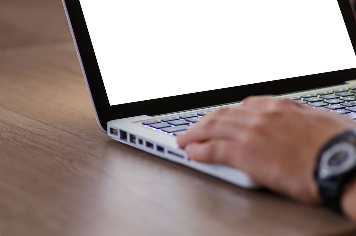 Pessoa trabalhando remotamente diante de um notebook em uma mesa organizada de home office.