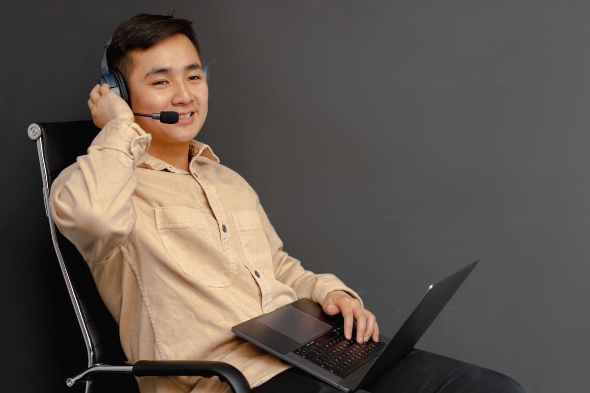Pessoa atendendo clientes em casa com computador e headset em uma mesa de home office.