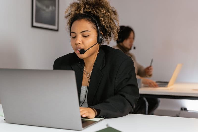 Vagas remotas de telemarketing: como funcionam e riscos African American woman working in customer support with a headset and laptop.