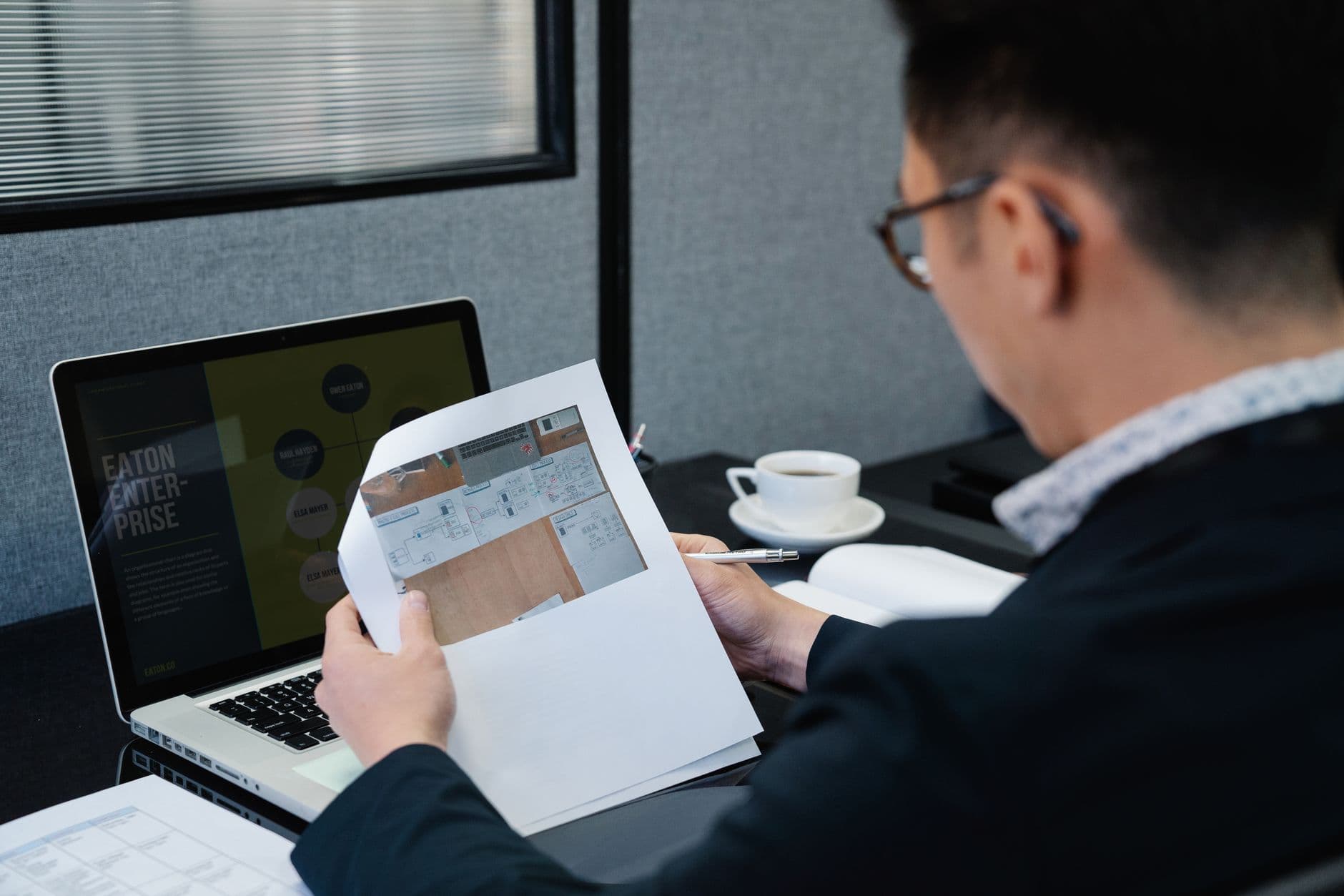 Vagas remotas para designer gráfico: como encontrar A man in an office setting analyzing documents with a laptop open nearby.