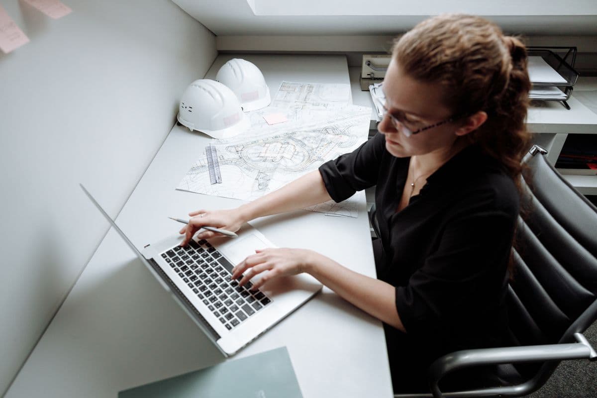Engenheira analisando projetos em um notebook em uma mesa de home office