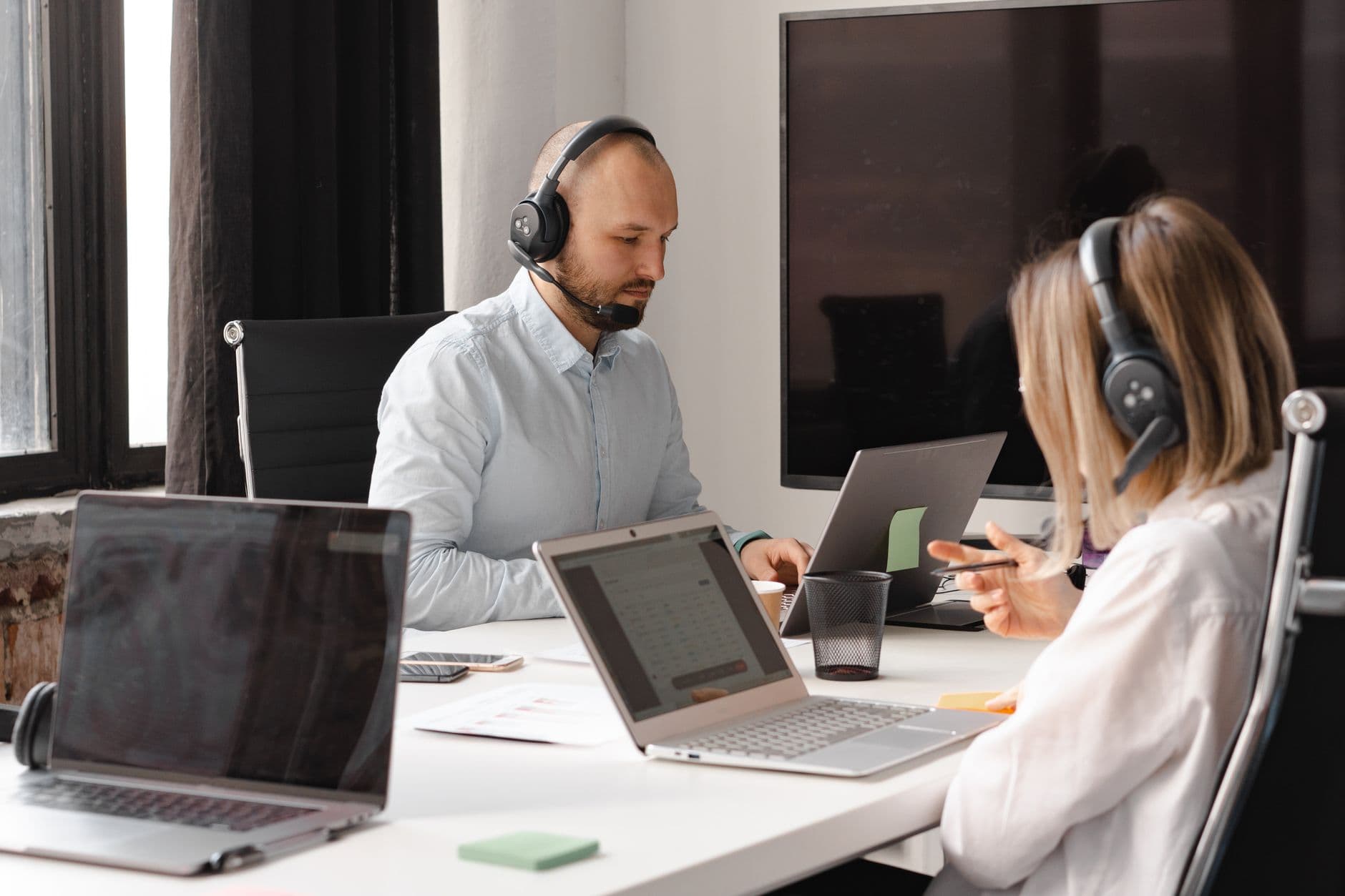 Vagas remotas de suporte técnico: como se preparar Customer support agents working together with laptops and headsets in an office setting.