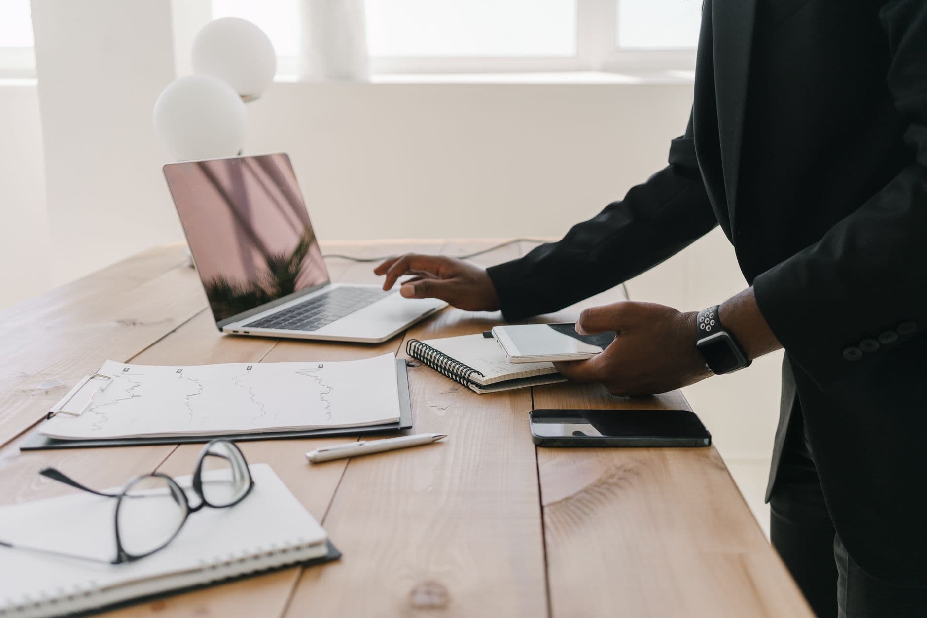 Vagas remotas na área de vendas: como encontrar Professional workspace with a laptop, documents, and stationery on a wooden table.