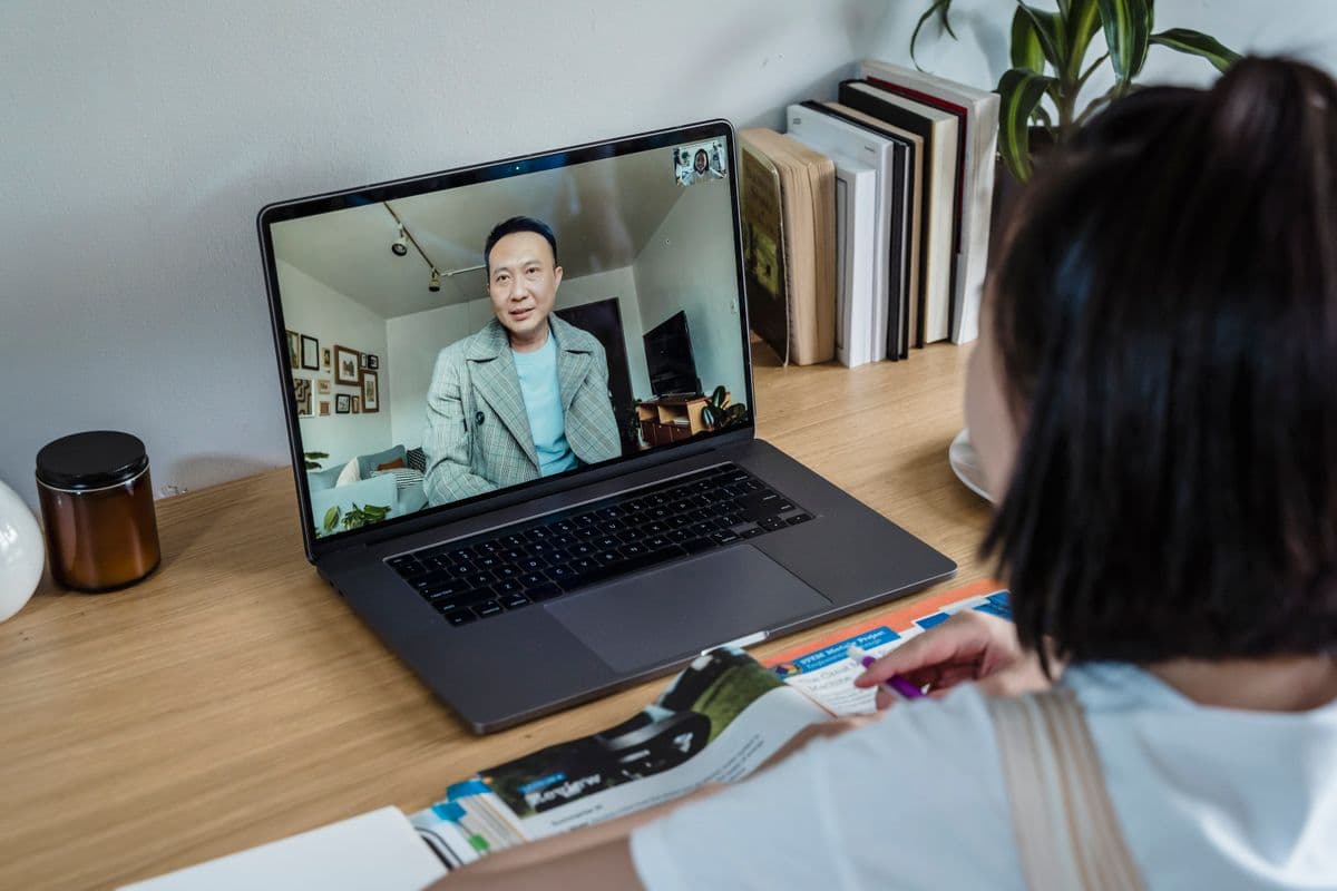 Pessoa trabalhando no laptop durante uma reunião remota por videochamada